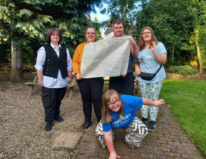 group of young people holding up a banner with writing on