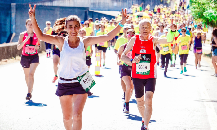Two people are running ahead of others at a marathon event. They are both cheering
