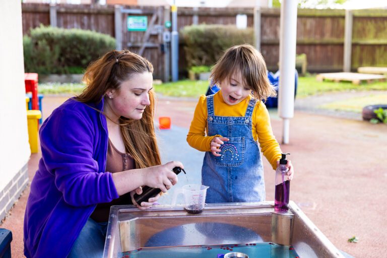 Nursery staff playing with disabled child